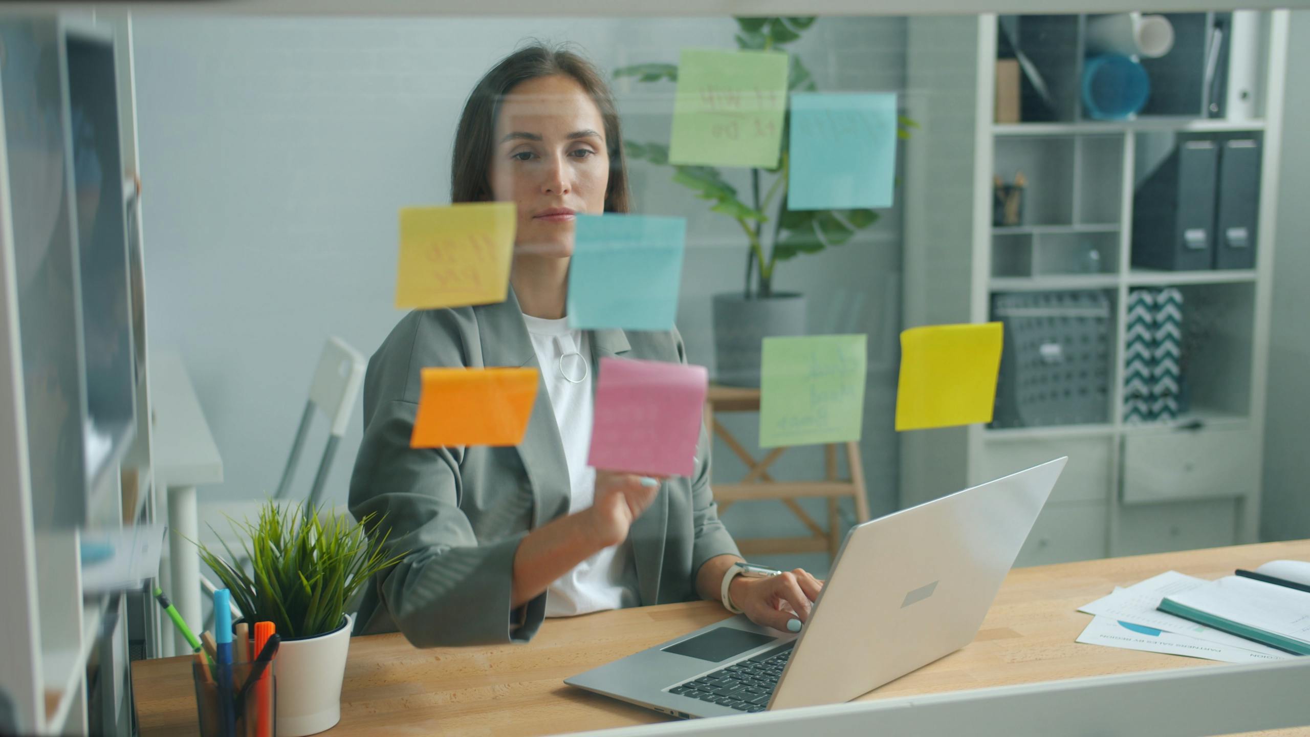 Businesswoman strategizing with sticky notes in a modern office environment.