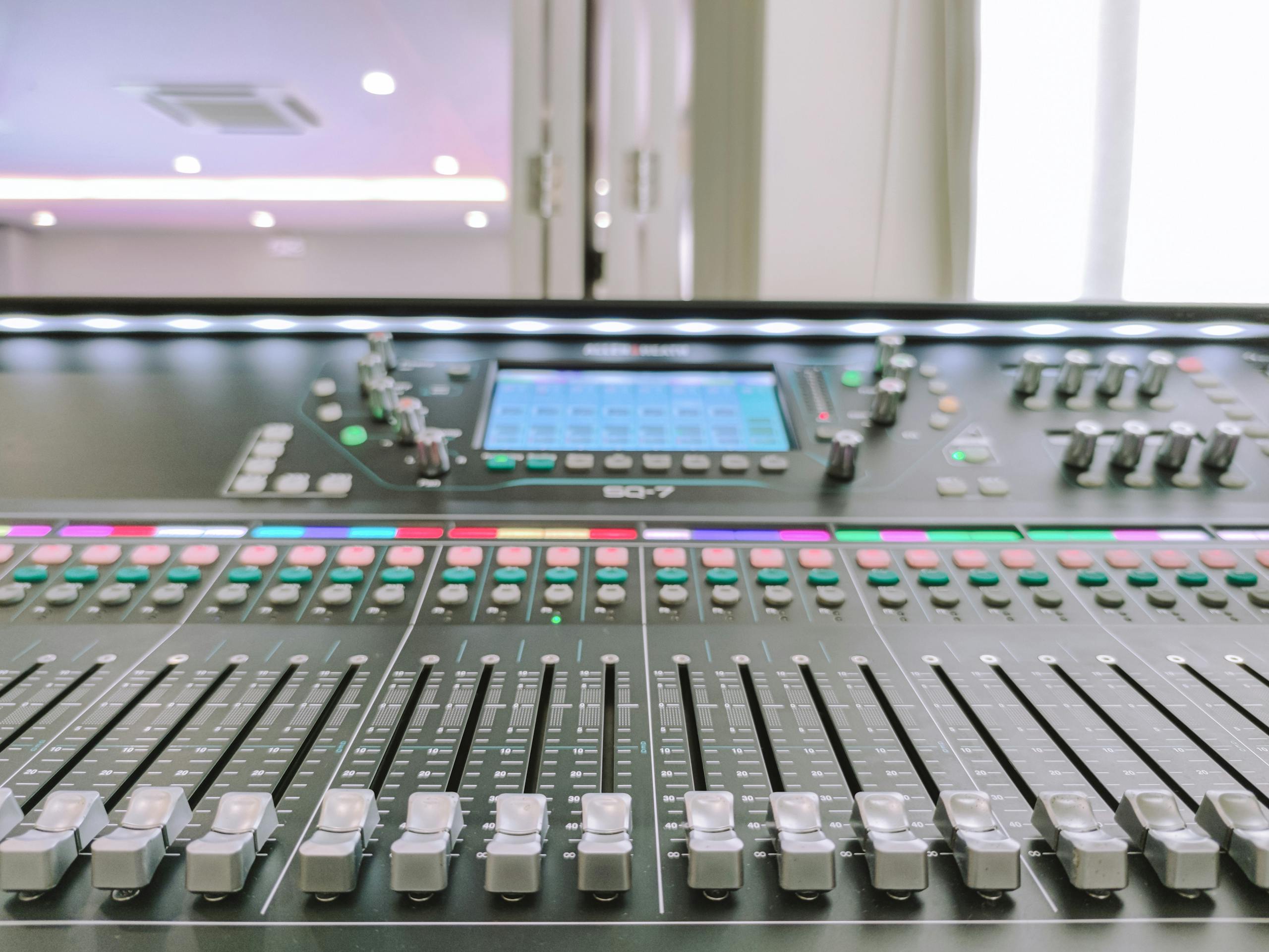 Close-up of an advanced audio mixer console with slide controls and digital display.